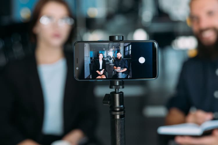 business man and woman shooting video using smartphone